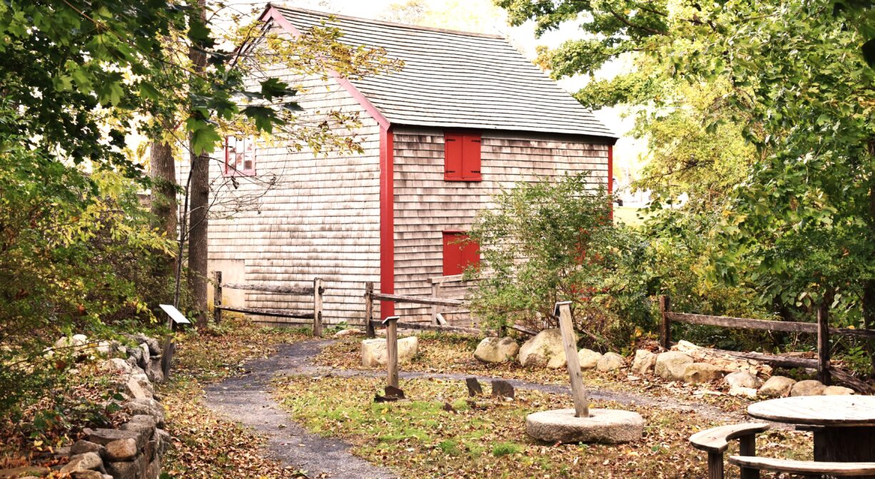 A photograph of a historic mill building with a park in the foreground.