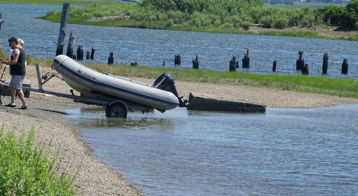 A photograph of two individuals hauling an inflatable boat out of a river.