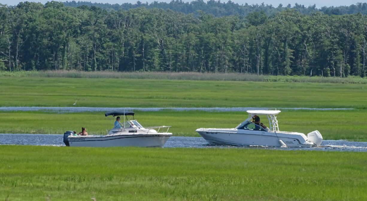 A photograph of two motorboats on a marsh creek.