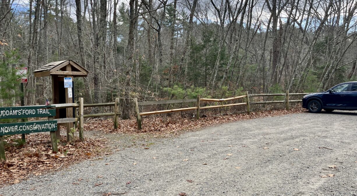 A photograph of an unpaved parking area at a forest trailhead.