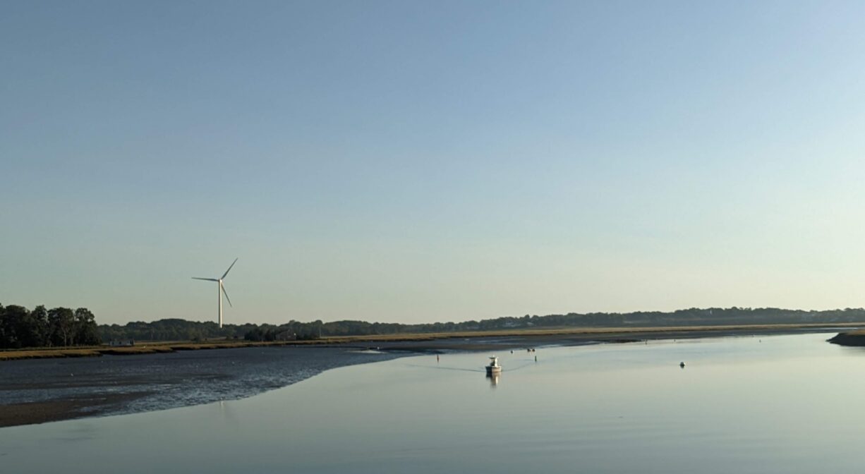 A photograph of a river at low tide with the remains of s shipwreck on one bank.