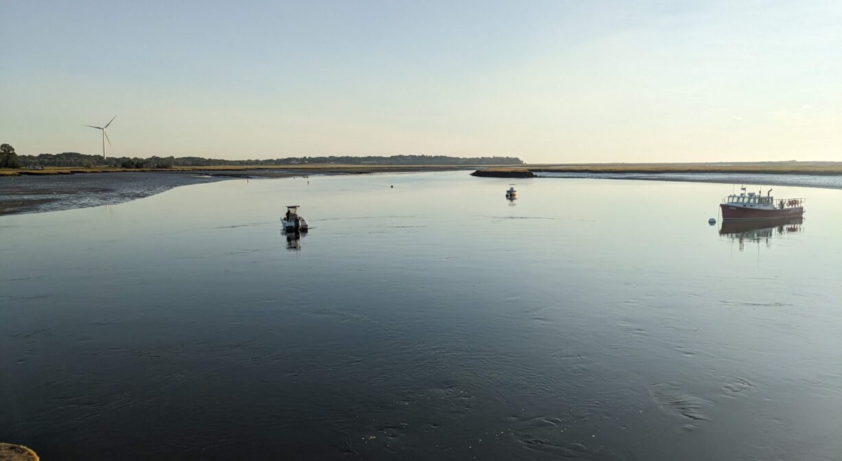 A photograph of a river at low tide with a shipwreck site on one bank.