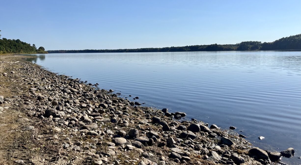 A photograph of a lake with a rocky shoreline.