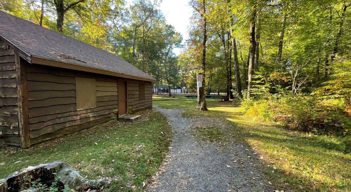 A photograph of a gravel trail beside a small wooden building.