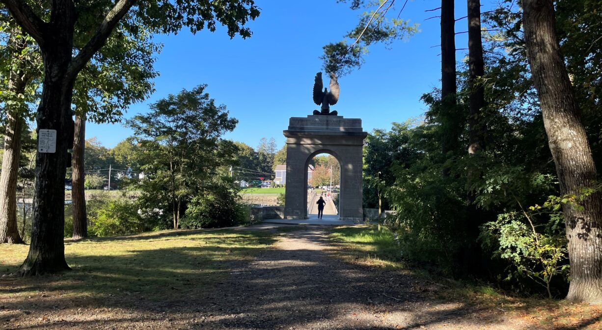 A photograph of a grassy park with a granite archway.