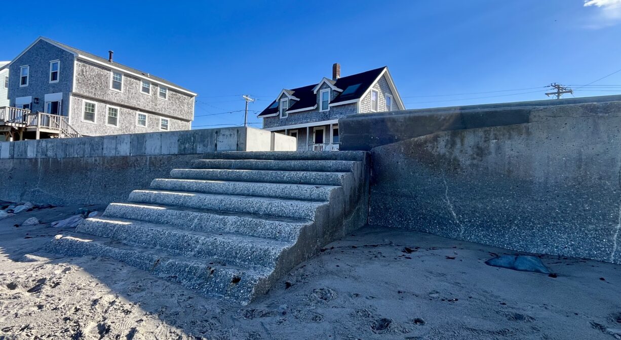 A photograph of a concrete staircase built into a sea wall on a beach.
