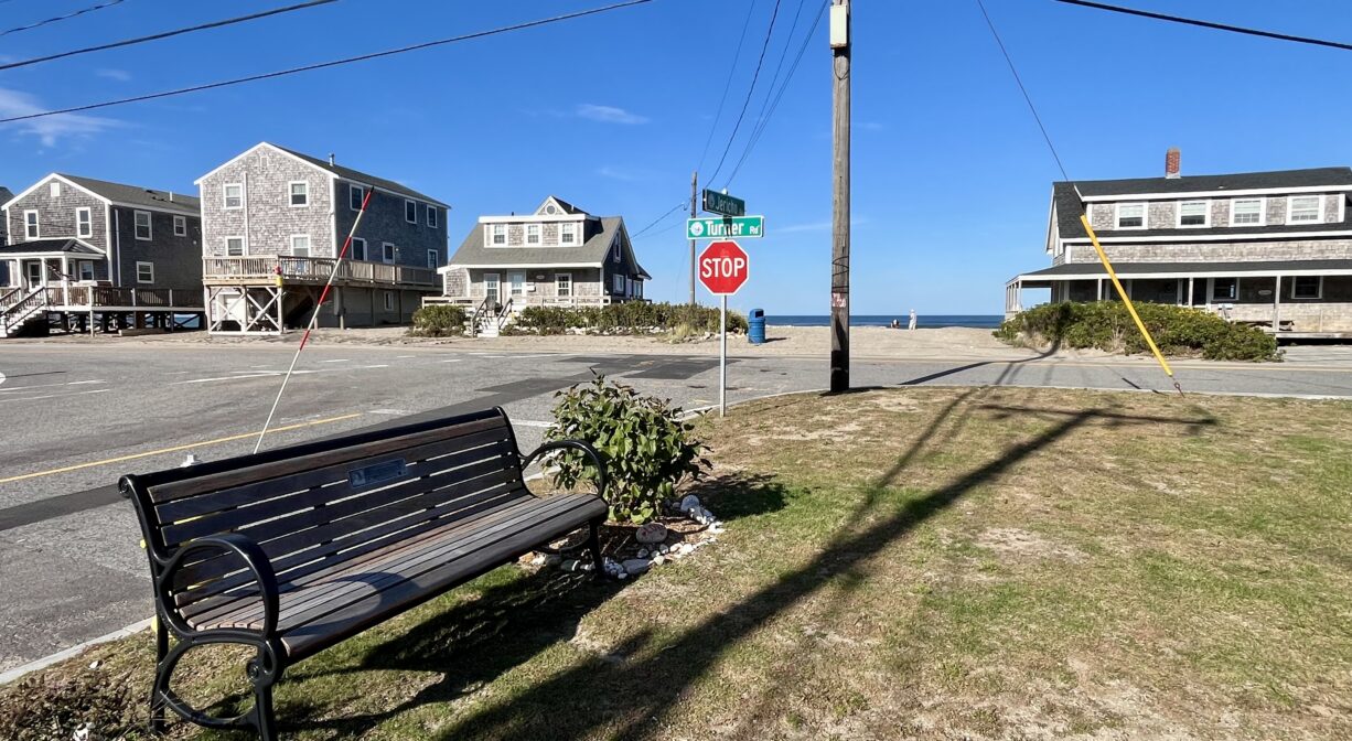 A photograph of a small grassy park near the entrance to an ocean beach.