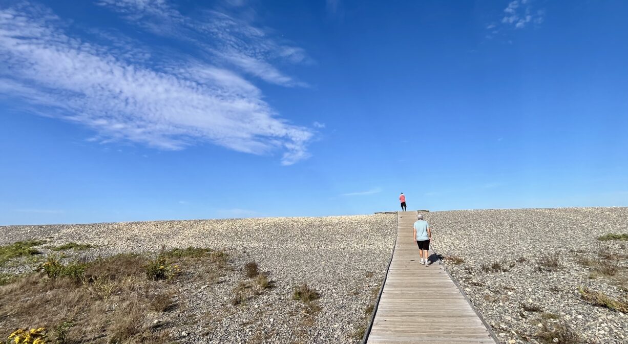 A photograph of two individuals walking up a beach boardwalk.