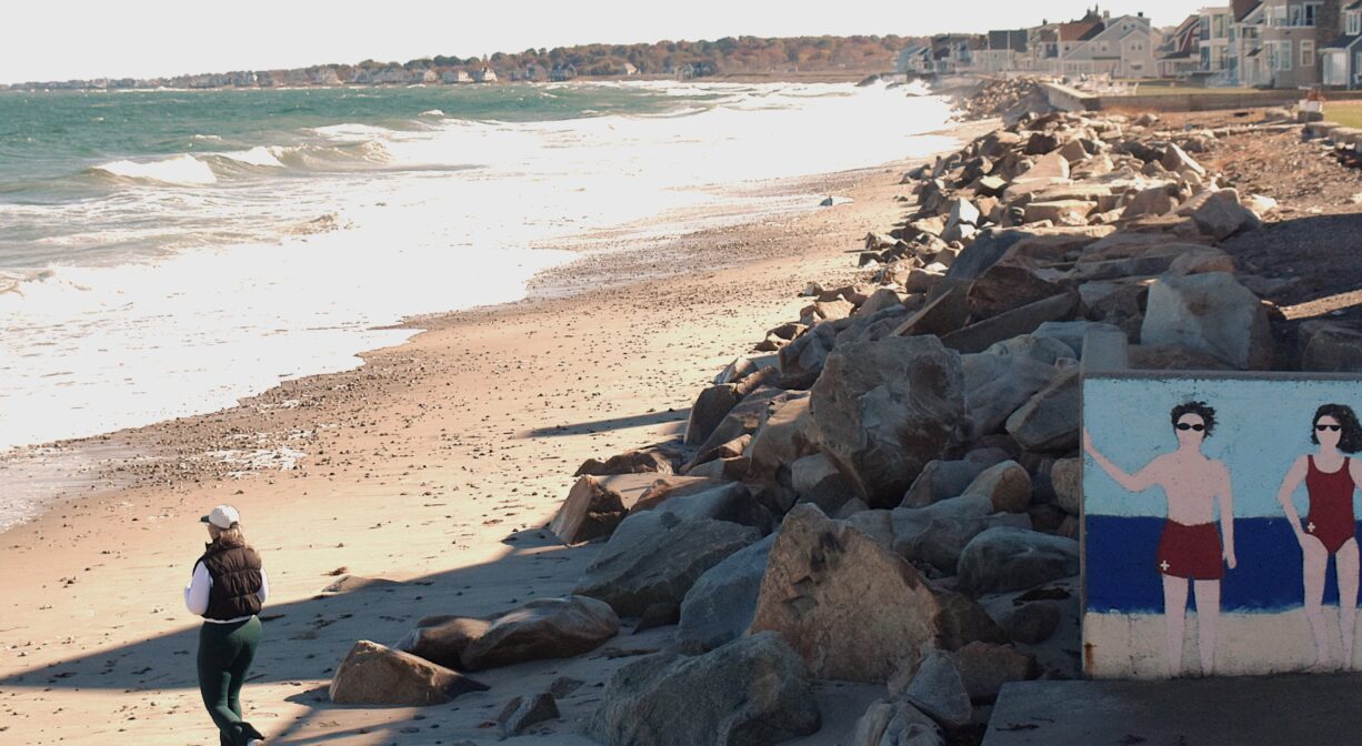 A photograph of the entrance to a beach with a mural on one side.