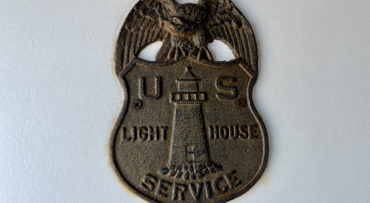 A photograph of a brass US Lighthouse Service logo.