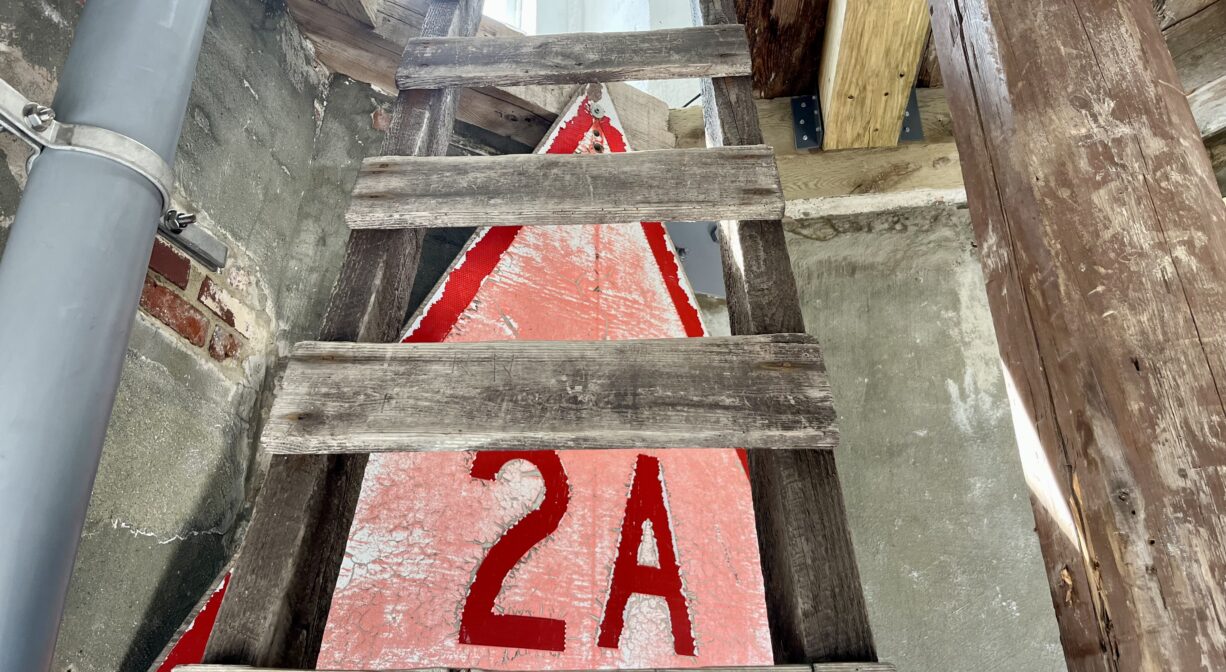 A photograph of a ladder and signage inside a lighthouse.