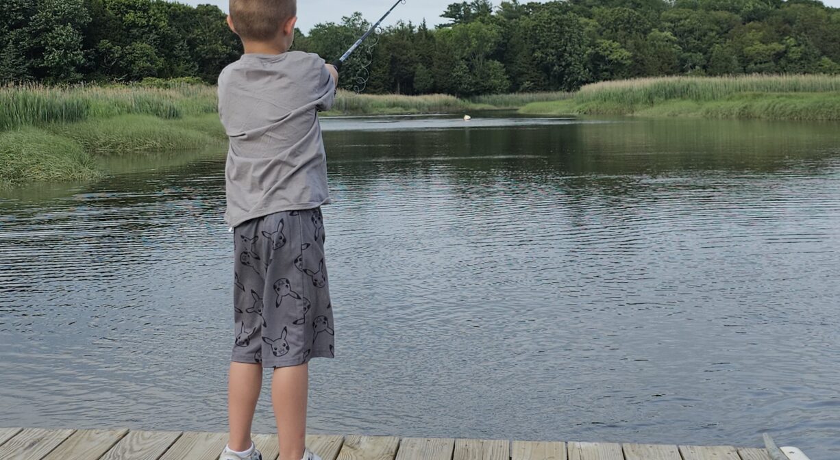 A photograph of a child fishing on a river from a float.