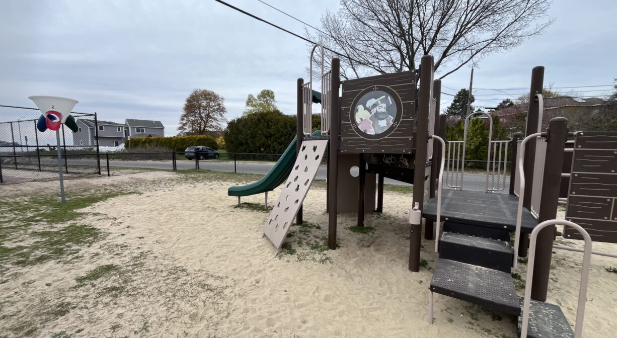 A photograph of a play structure with sand underfoot.