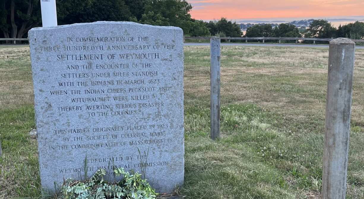 A photograph of a granite memorial in a grassy park at sunset.