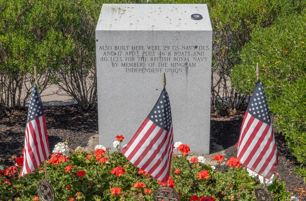 A photograph of a memorial with flags and ornamental plantings.
