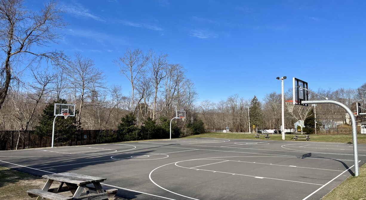 A photograph of two outdoor basketball courts with a picnic table in the foreground.
