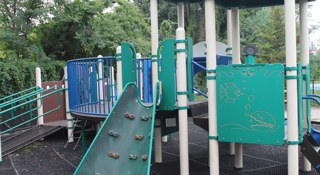 A photograph of a play structure with s climbing wall.