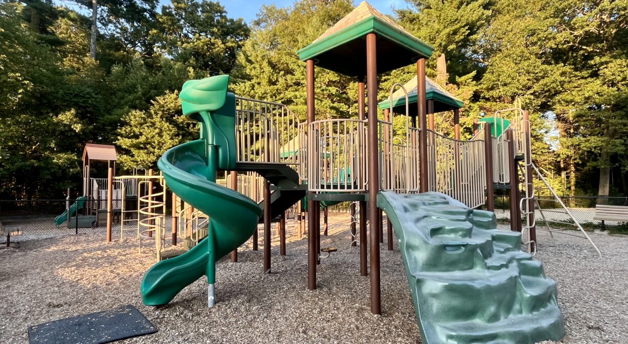 A photograph of a playground with green and brown play equipment.