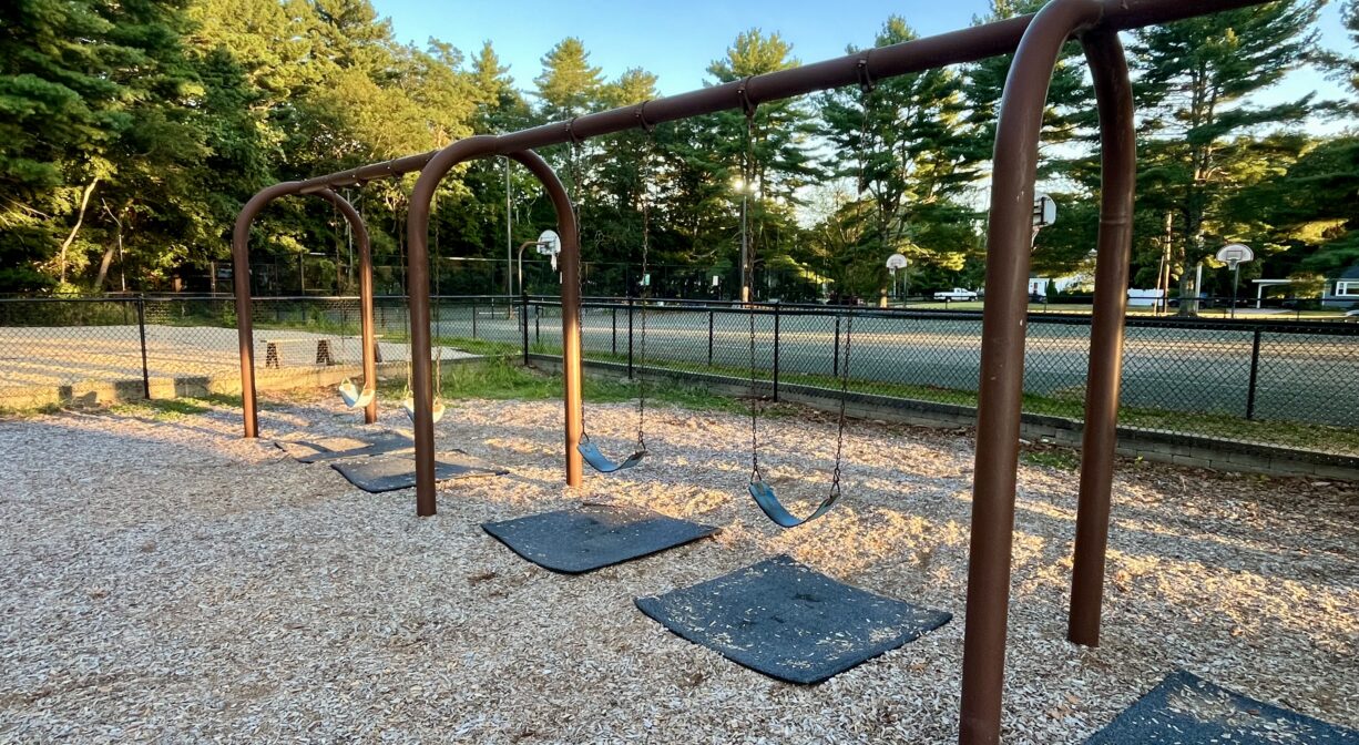 A photograph of a playground with a row of swings.