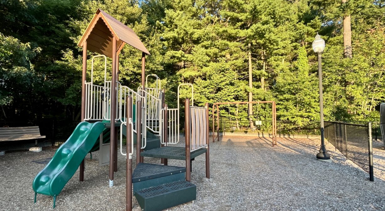 A photograph of a playground with green and brown play equipment.