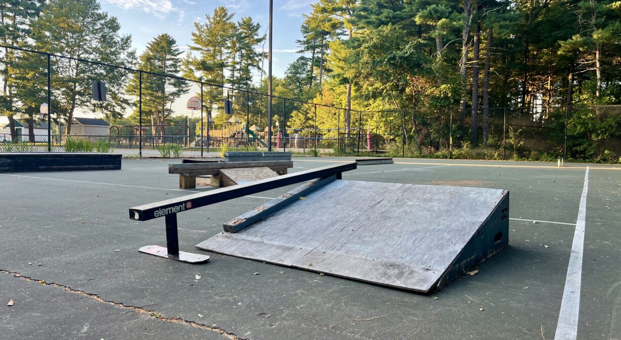 A photograph of a skate park with trees in the background.