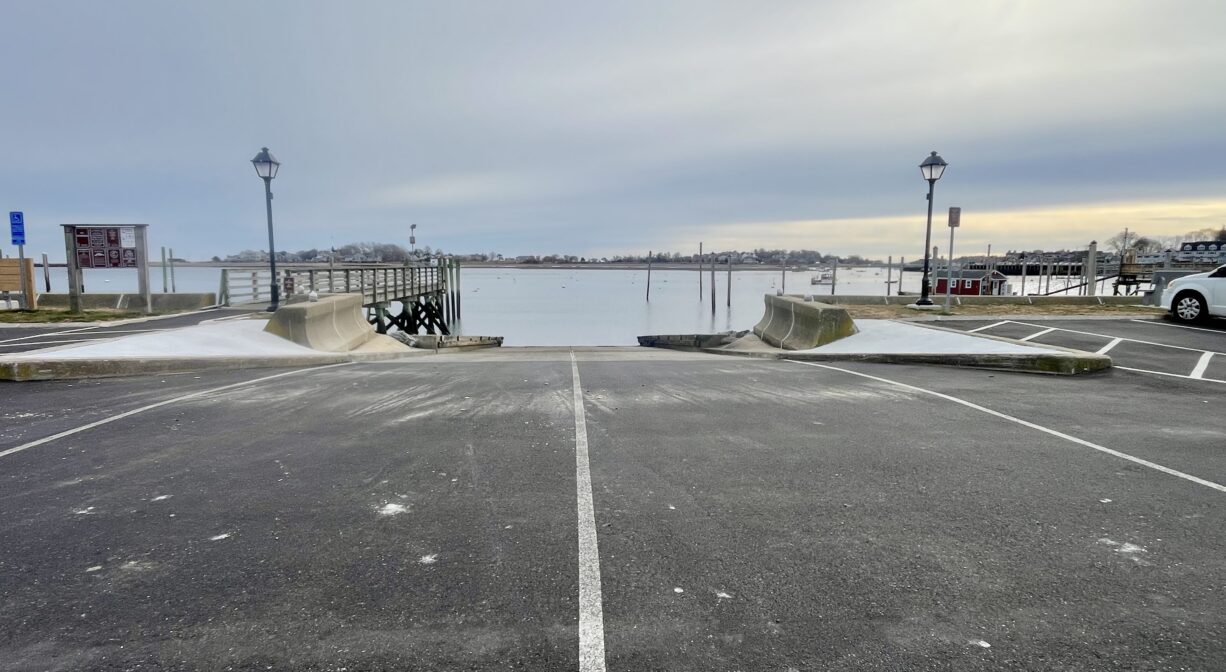 A photograph of a wide paved boat ramp on a harbor.