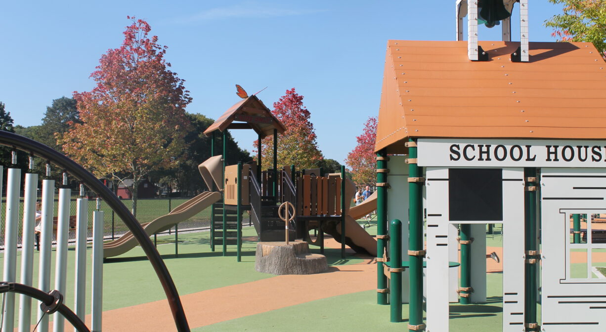 A photograph of a playground with a school house play structure.