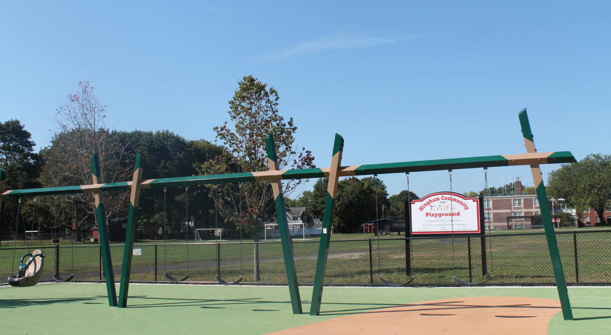 A photograph of a row of swings in a playground.