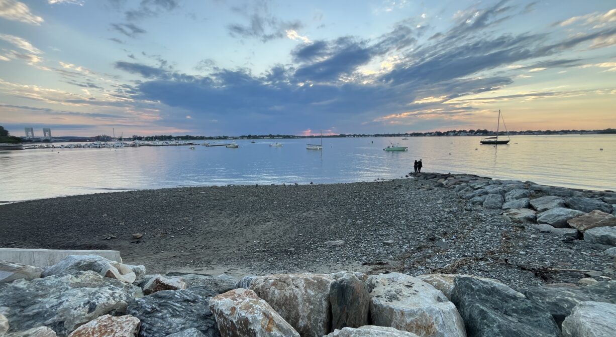 A photograph of a rocky beach at sunset.