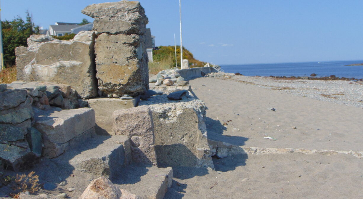 A stack of stone or concrete blocks at the edge of an ocean beach.