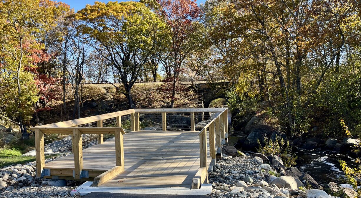 A photograph of a wooden viewing platform beside a river.