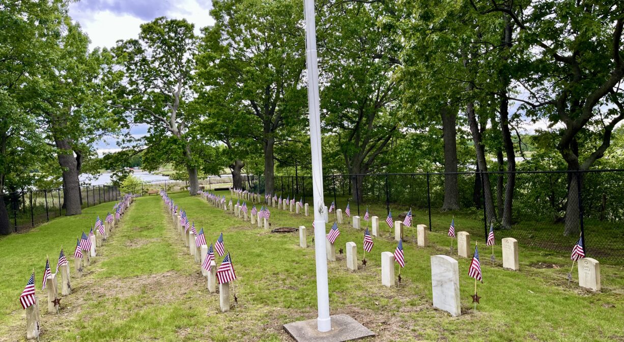 A photograph of a small cemetery with grass and trees.