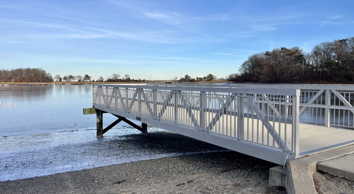 A photograph of a pier beside a marsh creek.