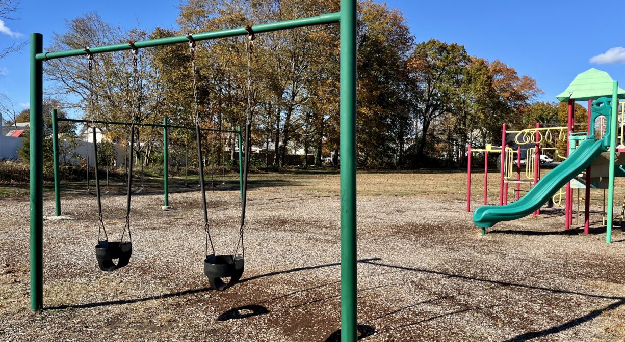 A photograph of a swing set and a play structure in a playground.