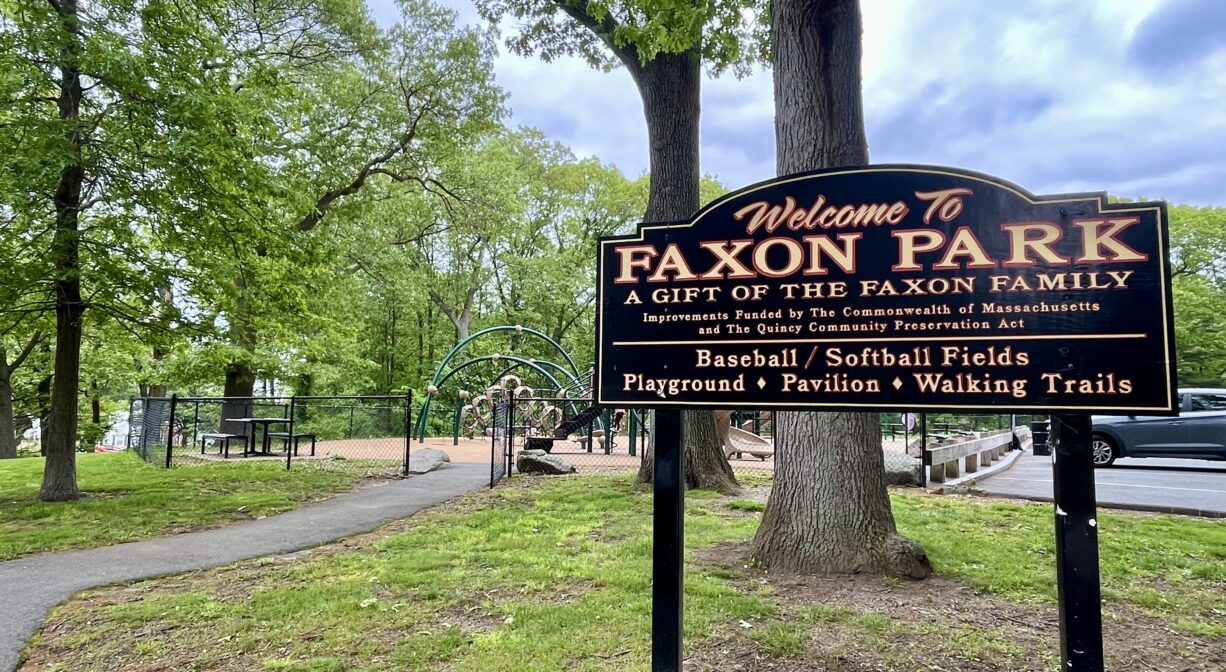 A photograph of a property sign in a grassy park.