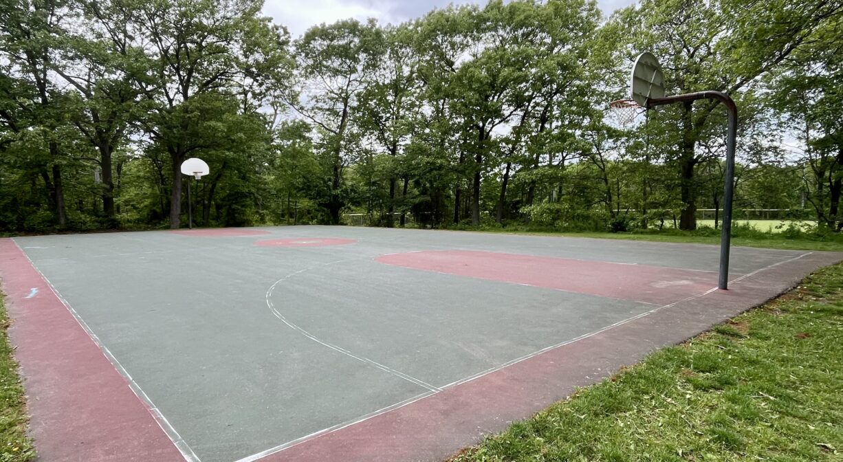 A photograph of a basketball court in a park.