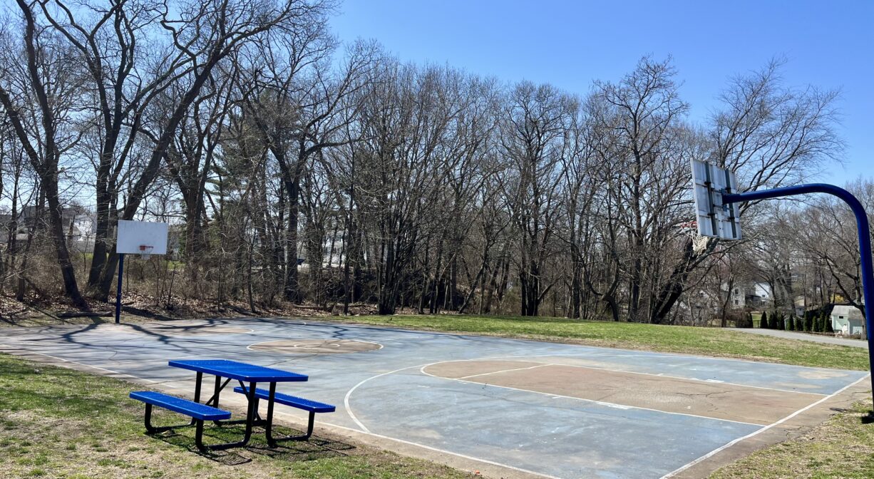 A photograph of a basketball court and a picnic table in a playground.