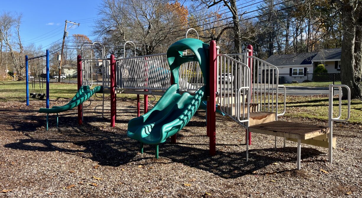 A photograph of a playground with green and red play equipment.