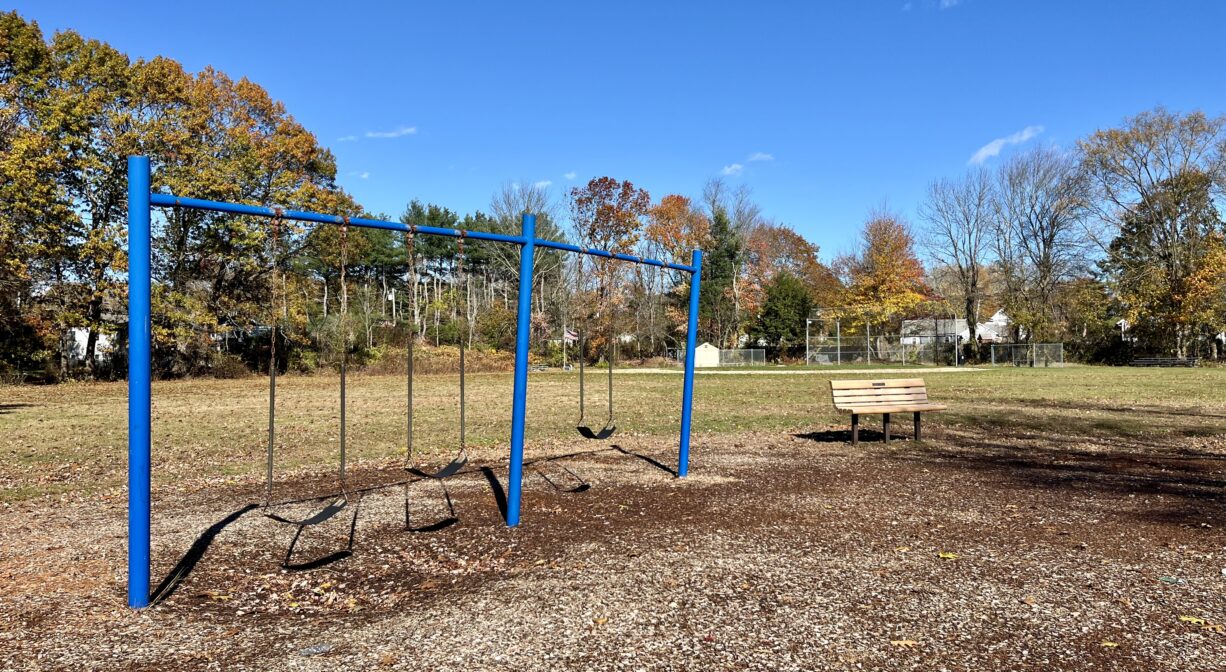 A photograph of a swing set in a playground.