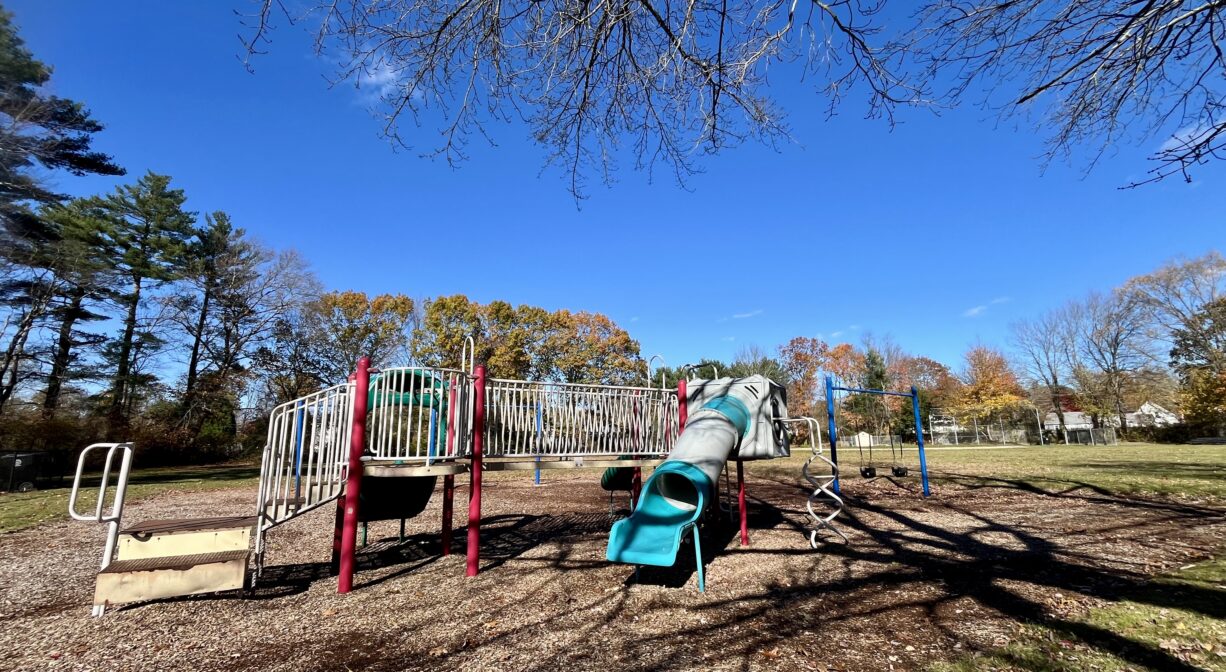 A photograph of a playground with green white, red and yellow play equipment