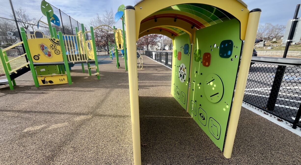 A photograph of a contemporary playground with green and yellow play equipment.