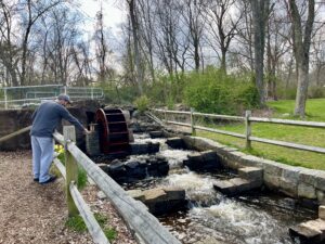 A photograph of a man pointing into a fishway in a park.